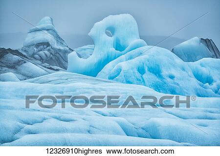 Stock Photograph - The large icebergs of Jokulsarlon, a glacial lagoon along the south coast of Iceland. The moody weather really brings out the blue ice; Iceland. Fotosearch