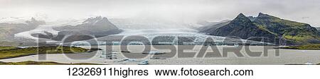 Stock Photograph - The majestic Fjallsarlon is an iceberg lagoon at the south end of the glacier Vatnajokull. On the lagoon, you can see floating icebergs that calf from the edge of the glacier; Iceland. Fotosearch