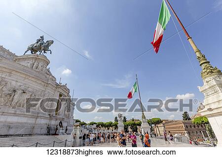 Stock Photograph - The Piazza Venezia and Monument to Vittorio Emanuele Unk0wn Soldier is guarded by Italian Military members in rememberance of WW1 soldiers and attracts many tourists year round to see the monument and flags flying near the forum and colosseum; Rome, Italy. Fotosearch