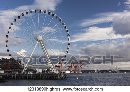 Stock Photograph - The Seattle Great Wheel, a giant ferris wheel at Pier 57 on Elliott Bay with an overall height of 175 feet, it was the tallest ferris wheel on the West coast of the United States when it opened on June 29, 2012, with dramatic clouds in the background;.... Fotosearch