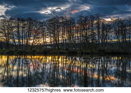 Stock Photograph - The sun rises along the Lewis and Clark River; Astoria, Oregon, United States of America. Fotosearch