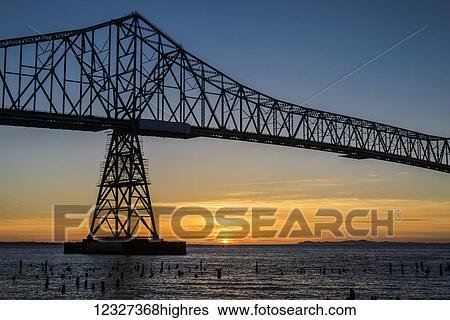 The sun sets beneath the Astoria-Megler Bridge; Astoria, Oregon, United States of America View Large Photo Image Stock Photograph - The sun sets beneath the Astoria-Megler Bridge; Astoria, Oregon, United States of America. Fotosearch