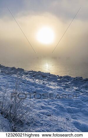 The sun shines through low altitude fog cast in warm light along Turnagain Arm and the Seward Highway, sea ice covering the ocean in the foreground, South-central Alaska; Anchorage, Alaska, United States of America View Large Photo Image Stock Photograph - The sun shines through low altitude fog cast in warm light along Turnagain Arm and the Seward Highway, sea ice covering the ocean in the foreground, South-central Alaska; Anchorage, Alaska, United States of America. Fotosearch