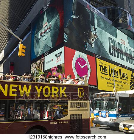 Stock Photograph - Tour bus on a street under large colourful billboards in Times Square; New York City, New York, United States of America. Fotosearch