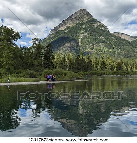Stock Photograph - Tourists walk along Upper Water Lake, Waterton Lakes National Park; Alberta, Canada. Fotosearch