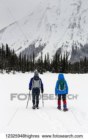 Stock Photograph - Two women snowshoeing in the mountains, East of Field; British Columbia, Canada. Fotosearch