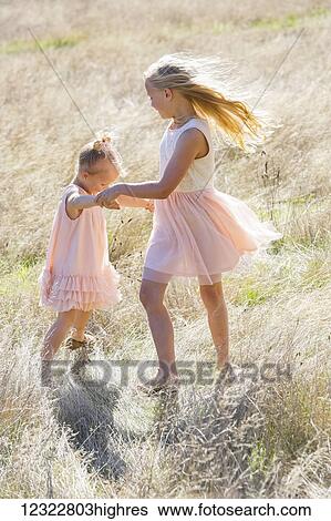 Stock Photograph - Two young girls dancing in a field of long grass; Washington, United States of America. Fotosearch