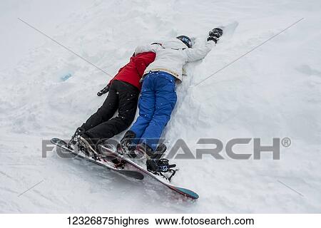 Two young snowboarders laying together resting in the snow; Whistler, British Columbia, Canada View Large Photo Image Stock Photograph - Two young snowboarders laying together resting in the snow; Whistler, British Columbia, Canada. Fotosearch