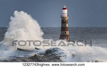 Stock Photograph - Waves splashing against Roker lighthouse at the end of a pier; Sunderland, Tyne and Wear, England. Fotosearch