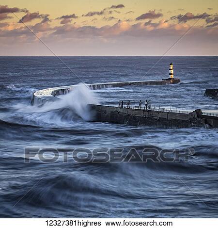 Waves splashing on the pier with a glowing sky at sunset; Seaham, County Durham, England View Large Photo Image Stock Photograph - Waves splashing on the pier with a glowing sky at sunset; Seaham, County Durham, England. Fotosearch