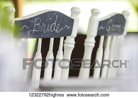 White wooden chairs side by side with bride and groom written in chalk on a chalkboard finish on the back View Large Photo Image Stock Photograph - White wooden chairs side by side with bride and groom written in chalk on a chalkboard finish on the back. Fotosearch