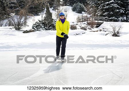 Woman skating on frozen pond with snow covered wooden bridge in the background; Calgary, Alberta, Canada View Large Photo Image Stock Photograph - Woman skating on frozen pond with snow covered wooden bridge in the background; Calgary, Alberta, Canada. Fotosearch