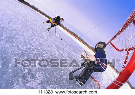 Young boys playing ice hockey outdoors View Large Photo Image Stock Photo - Young boys playing ice hockey outdoors. Fotosearch