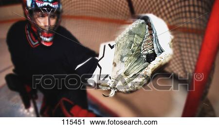 Stock Image - Young goalie in net with glove extended. Fotosearch