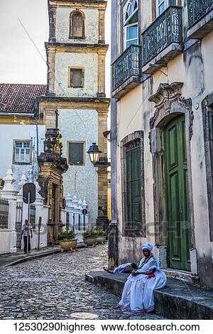 Stock Photograph - A bahaian women sits waiting in the streets in Peloriniho, the old part of Slavador; Salvador, Bahia, Brazil. Fotosearch