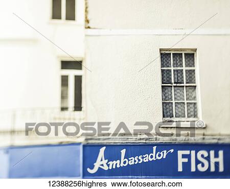 Stock Photograph - A blue Ambassador Fish restaurant sign on a white building; England. Fotosearch