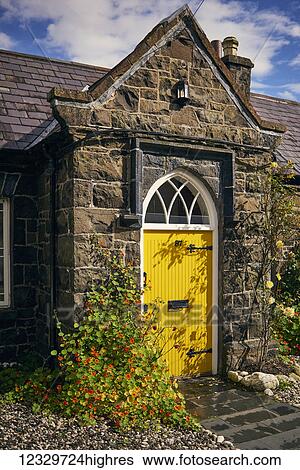 Stock Photograph - A Bright Yellow Front Door On A Stone House; Ireland. Fotosearch