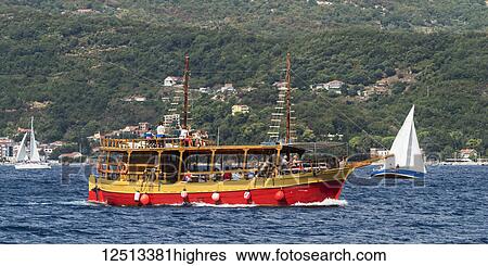 Stock Photograph - A colourful boat full of passengers in the Bay of Kotor off the coast of Herceg Novi; Opstina Herceg Novi, Monte. Fotosearch