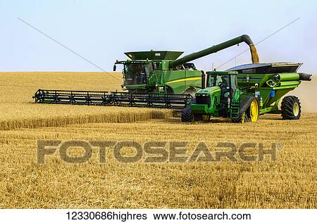 Stock Photograph - A Combine Offloading Grain To A Tractor Pulled Grain Cart In Southwest Washington; Washington, United States Of America. Fotosearch
