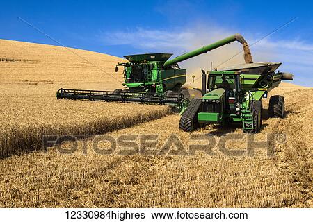 Stock Photograph - A Combine Offloading Grain To A Tractor Pulled Grain Cart In Southeast Washington; Washington, United States Of America. Fotosearch
