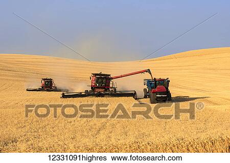 Stock Photograph - A Combine Offloading Grain To A Tractor Pulled Grain Cart In Southeast Washington; Washington, United States Of America. Fotosearch