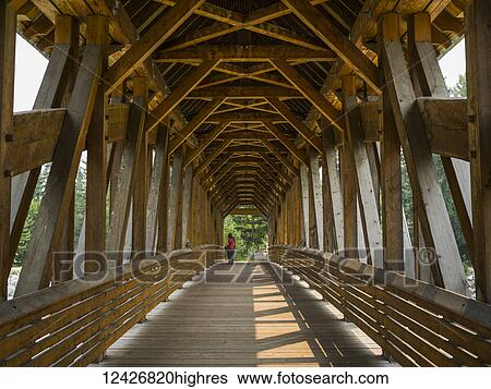 Stock Photograph - A couple standing at the end of a wooden covered bridge; Golden, British Columbia, Canada. Fotosearch