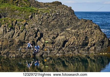 Stock Photograph - A Father And Son Fishing In The Tide Pools Along The Coast Of Northern Ireland; Ireland. Fotosearch