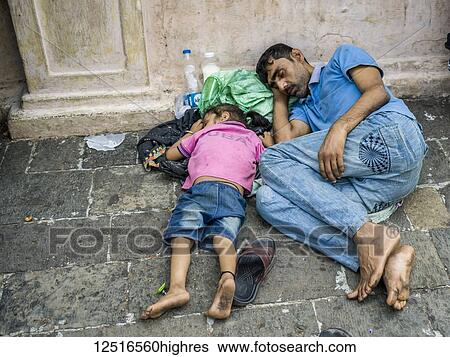 Stock Photograph - A father and young daughter sleep on the streets of Mumbai, India. Fotosearch