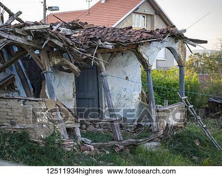 Stock Photograph - A house in disrepair with the roof torn to pieces and the pillars in front broken and leaning; Kostol, Mehedin? i County, Serbia. Fotosearch
