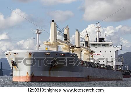 Stock Photograph - A large container ship in Burrard Inlet waiting to dock at the Port of Vancouver; Vancouver, British Columbia, Canada. Fotosearch