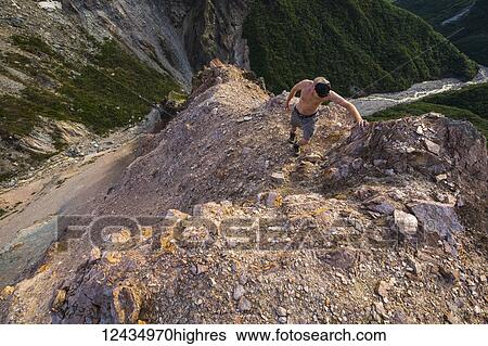 Stock Photograph - A man climbs a steep ridge above Whistler Creek in the eastern Alaska Range; Alaska, United States of America. Fotosearch