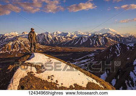 A man on a snowy ridge near Polychrome Mountain in Denali National Park faces the sunset with Denali in the background; Alaska, United States of America View Large Photo Image Stock Photograph - A man on a snowy ridge near Polychrome Mountain in Denali National Park faces the sunset with Denali in the background; Alaska, United States of America. Fotosearch