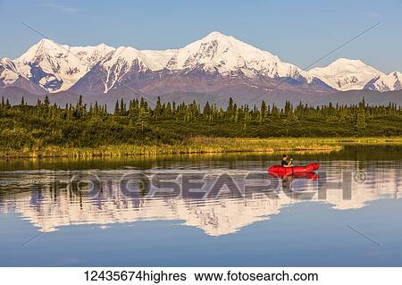 A man paddles across Donnelly Lake in a pack raft with Mt. Moffit and the Alaska Range reflecting on the water; Alaska, United States of America View Large Photo Image Stock Photograph - A man paddles across Donnelly Lake in a pack raft with Mt. Moffit and the Alaska Range reflecting on the water; Alaska, United States of America. Fotosearch