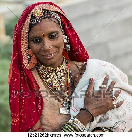 Stock Photograph - A mother holding her sleepy baby; Jaisalmer, Rajasthan, India. Fotosearch