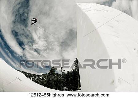 Stock Photograph - A professional snowboarder flipping mid-air at Heavenly Resort; South Lake Tahoe, California, United States of America. Fotosearch