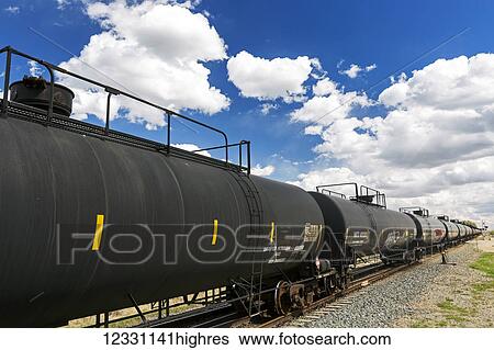 Stock Photograph - A Row Of Rail Oil Tank Containers With Clouds And Blue Sky; Alberta, Canada. Fotosearch