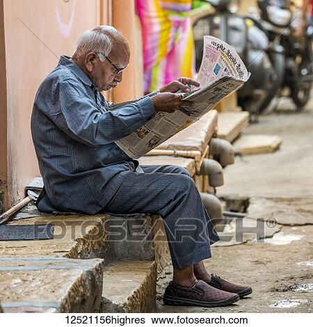 A senior man sits on the side of a street reading the newspaper; Jaisalmer, Rajasthan, India View Large Photo Image Stock Photograph - A senior man sits on the side of a street reading the newspaper; Jaisalmer, Rajasthan, India. Fotosearch