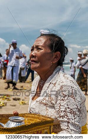 Stock Photograph - A Senior Women At A Religious Ceremony On The Beach; Bali, Indonesia. Fotosearch