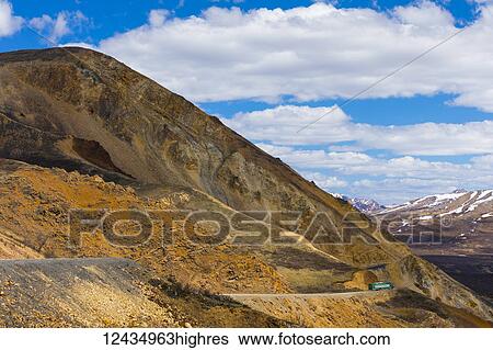 Stock Photograph - A shuttle bus winds around cliffs near Polychrome Pass in Denali National Park; Alaska, United States of America. Fotosearch