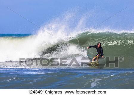 A surfer rides a wave at Pelican Beach on the Atlantic ocean in Florida; Satellite Beach, Florida, United States of America View Large Photo Image Stock Photograph - A surfer rides a wave at Pelican Beach on the Atlantic ocean in Florida; Satellite Beach, Florida, United States of America. Fotosearch