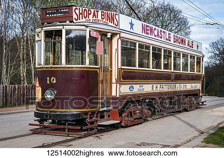 A tram with advertisements on the outside sits on a track along a street; Beamish, County Durham, England View Large Photo Image Stock Photograph - A tram with advertisements on the outside sits on a track along a street; Beamish, County Durham, England. Fotosearch
