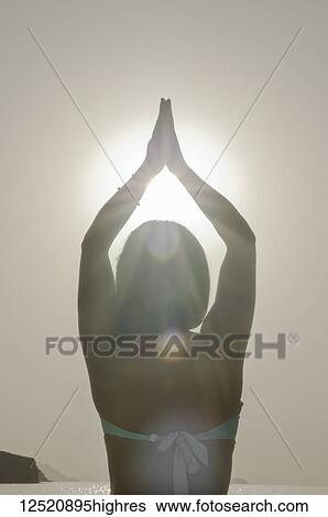 A woman backlit by the glowing sunlight doing a yoga pose by the water in a bikini; Alicante, Spain View Large Photo Image Stock Photograph - A woman backlit by the glowing sunlight doing a yoga pose by the water in a bikini; Alicante, Spain. Fotosearch