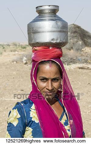 A woman carrying a jug on her head; Jaisalmer, Rajasthan, India View Large Photo Image Stock Photograph - A woman carrying a jug on her head; Jaisalmer, Rajasthan, India. Fotosearch