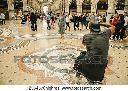 Stock Photograph - A woman in a dress poses for a photographer in the Galleria Vittorio Emanuele II shopping mall; Milan, Italy. Fotosearch