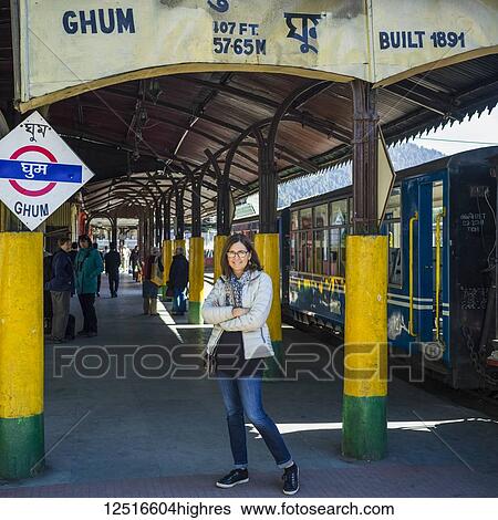 Stock Photograph - A woman standing at a station for the Darjeeling Toy Train, The Darjeeling Himalayan Railway; Ghoom, West Bengal, India. Fotosearch