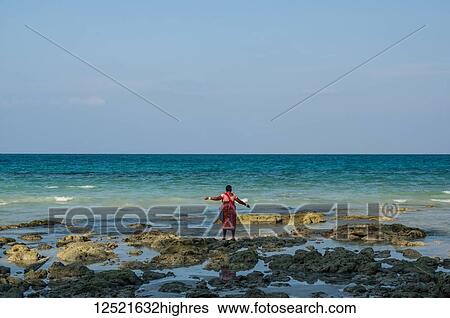 A woman stands with arms outstretched at the water's edge with a view of the horizon; Andaman Islands, India View Large Photo Image Stock Photograph - A woman stands with arms outstretched at the water's edge with a view of the horizon; Andaman Islands, India. Fotosearch