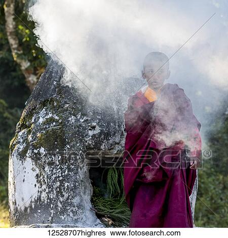 A young Buddhist monk stands outside in a shroud of smoke at Rinchenpong Monastery; Sikkim, India View Large Photo Image Stock Photograph - A young Buddhist monk stands outside in a shroud of smoke at Rinchenpong Monastery; Sikkim, India. Fotosearch