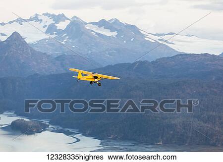 Stock Photograph - Aerial View Of A Piper J-3 Cub Flying Near Kenai Mountains, Kachemak Bay State Park, Southcentral Alaska, USA. Fotosearch