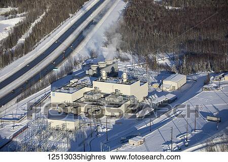 Stock Photograph - Aerial view of snow covering the grounds of the municipal light and power plant along the Glenn Highway, steam rising from the large smoke stacks atop the building, South-central Alaska in winter; Anchorage, Alaska, United States of America. Fotosearch