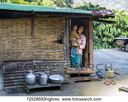 Stock Photograph - An Indian mother holds her young son in the doorway of their home; Bhalu Khop Village, Sikkim, India. Fotosearch